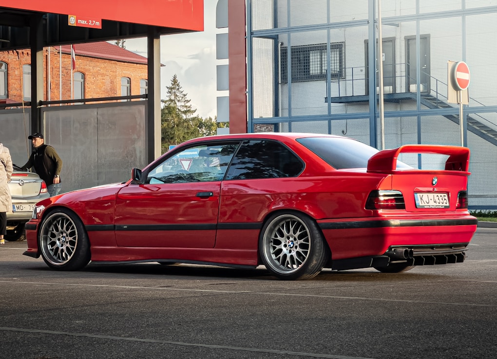 BMW 3 Series E36: The Last Cheap RWD Manual BMW Worth Buying? 7 a red BMW E36 coupe parked in a parking lot next to a building