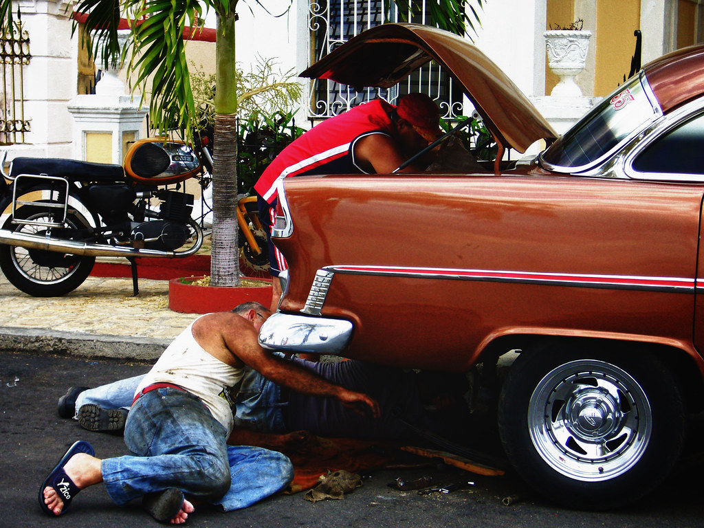 People working on a car in Cuba