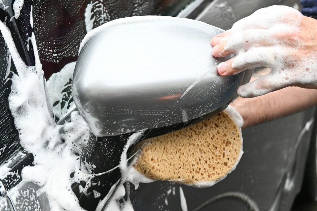 Unpopular Opinion: Is Car Detailing Making You Anxious to Drive? 3 a person washing a car with a sponge