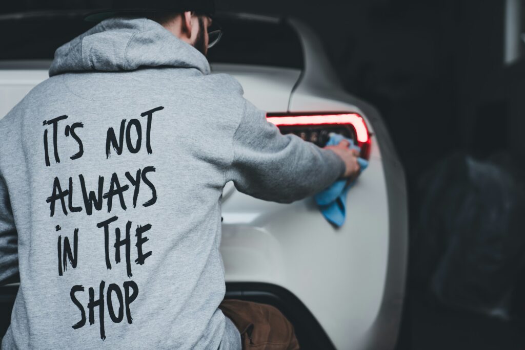 a man cleaning a car with a cloth wearing a car enthusiast hoodie