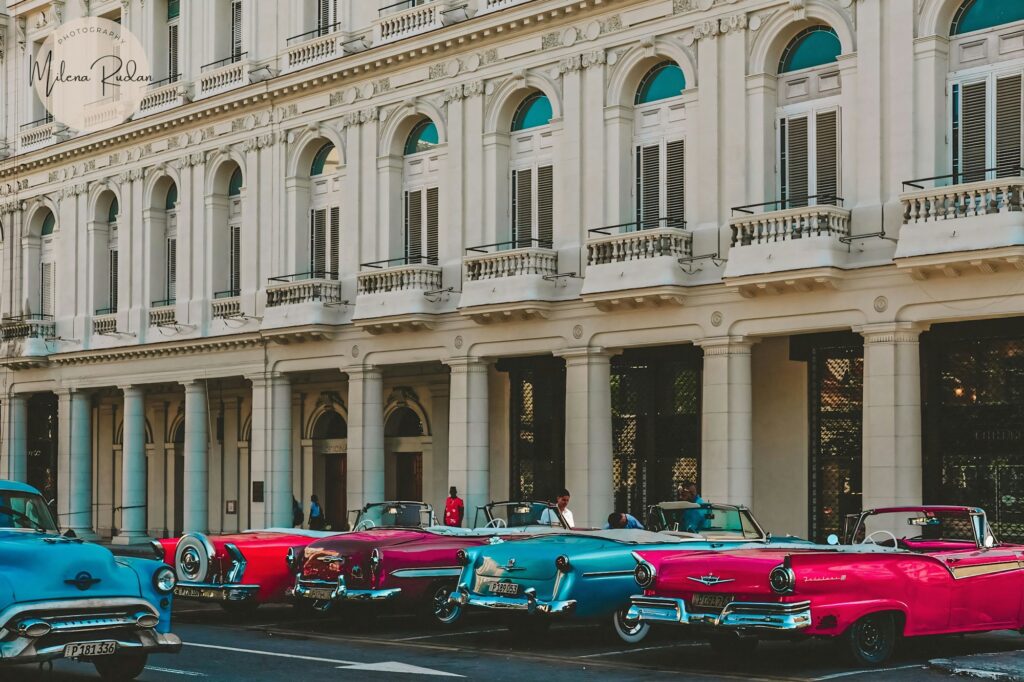 A row of classic cars (almendrones) parked in front of a building in Cuba